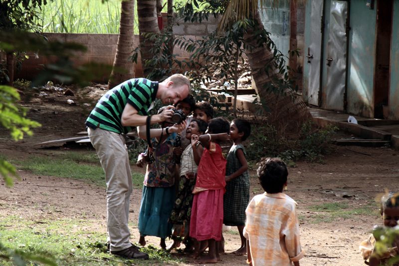 Andrew showing a camera screen to a group of laughing children