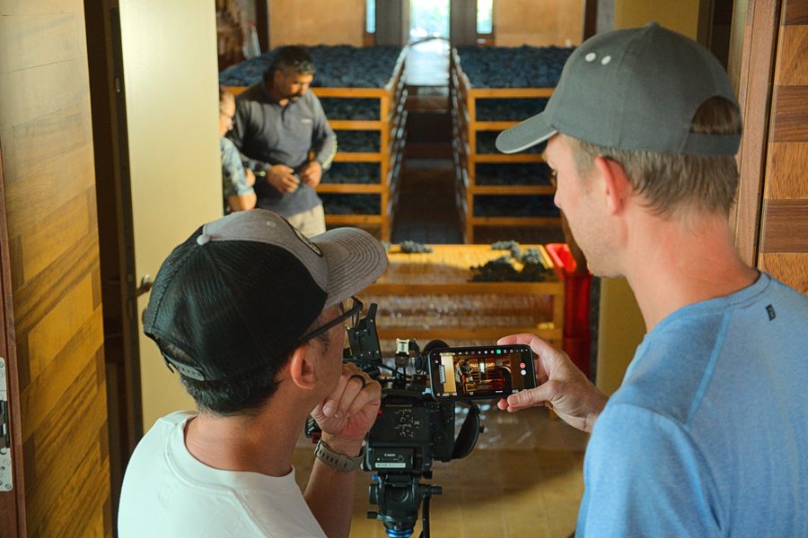 Andrew and Patrick Shen reviewing a shot beside racks of drying grapes
